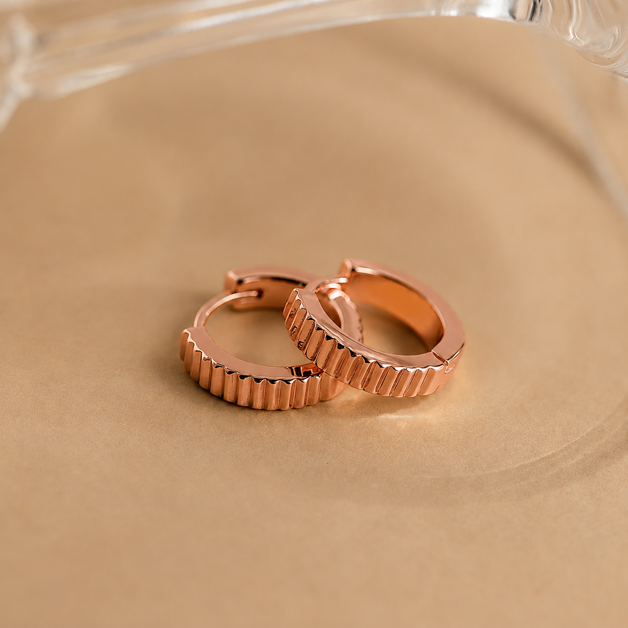 Rose gold hoop earrings on a beige surface