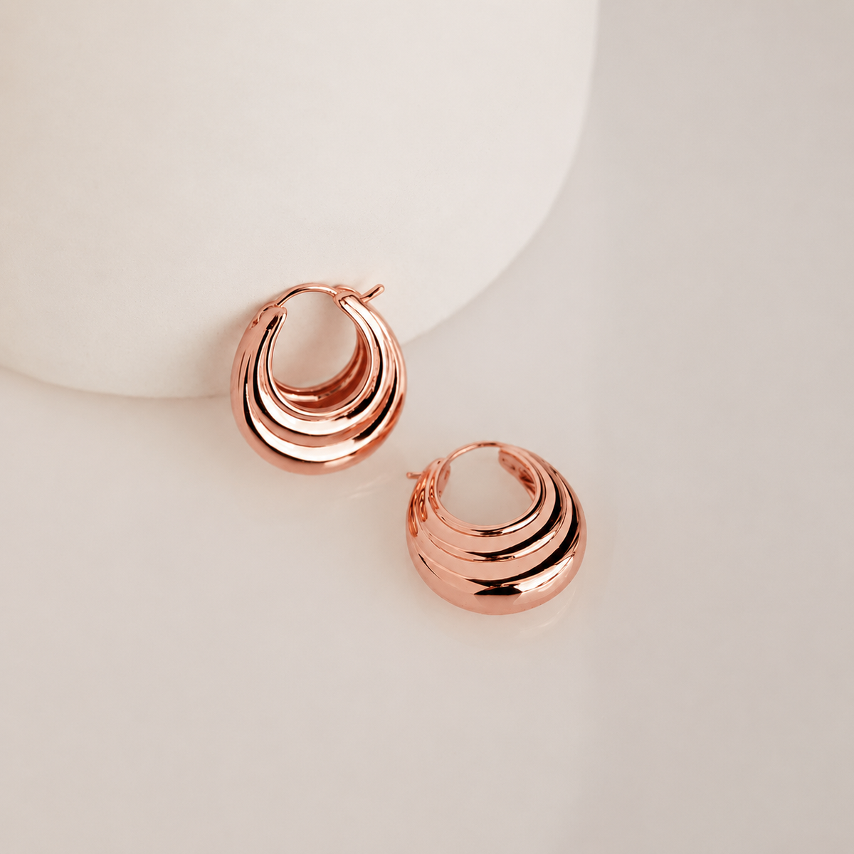 Rose gold hoop earrings on a light background