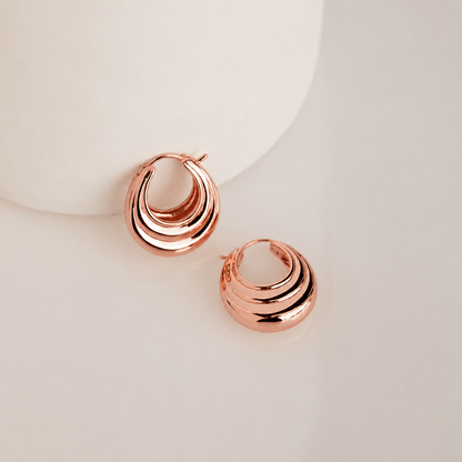 Rose gold hoop earrings on a light background