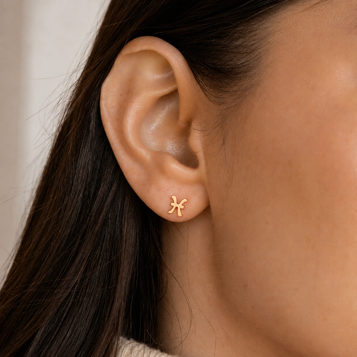 Close-up of an ear wearing a gold earring with a star design.