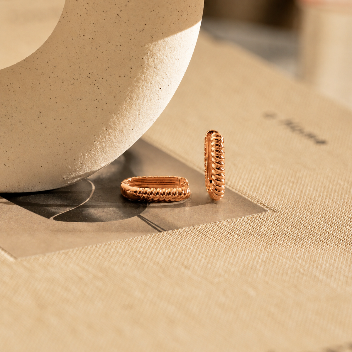 Two gold rings on a textured beige surface