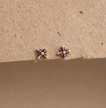 Rose gold earrings with black gemstones on a beige background