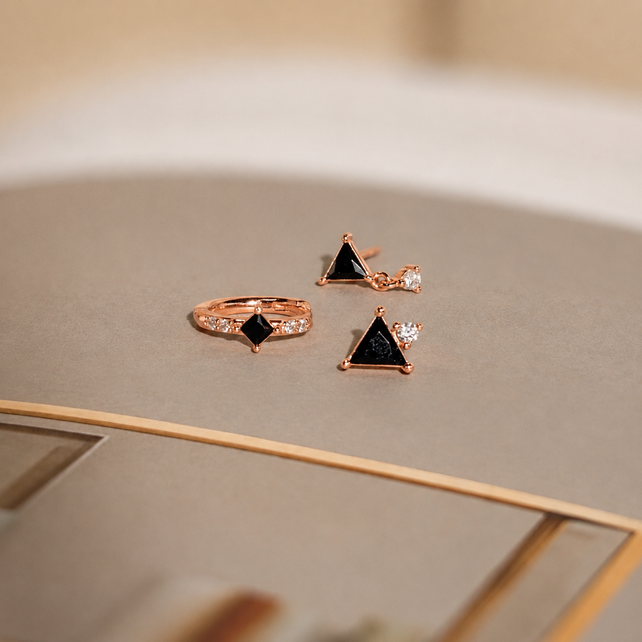 Rose gold jewelry set with black gemstones on a neutral background