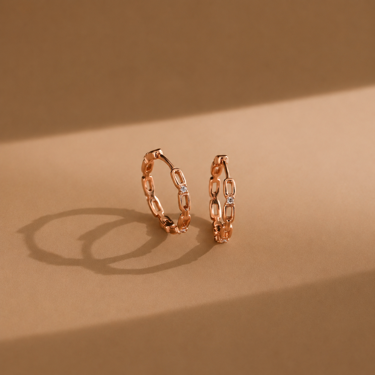 Rose gold hoop earrings on a brown background