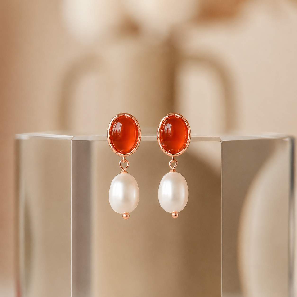 Pair of earrings with red gemstones and pearl drops on a reflective surface.