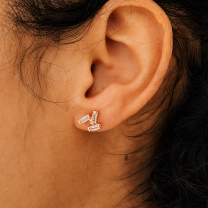 Close-up of an ear wearing gold stud earrings with a blurred background