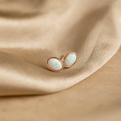 Pair of opal stud earrings on beige fabric