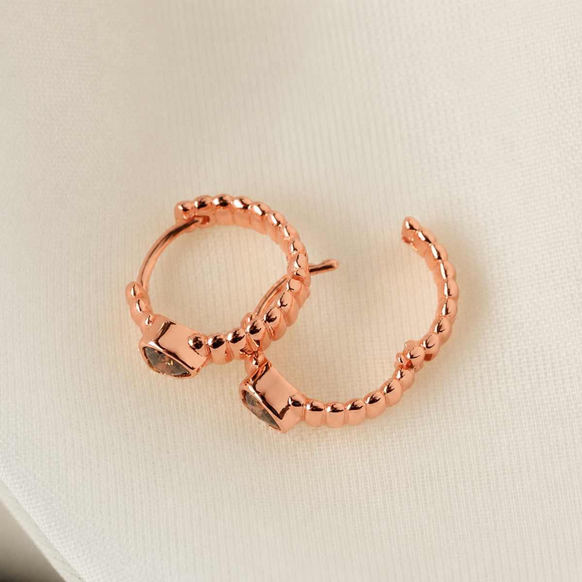 Rose gold hoop earrings on a light beige background