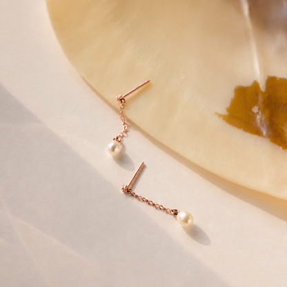 Rose gold earrings with pearls on a light background