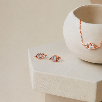 Rose gold earrings with gemstones on a beige surface
