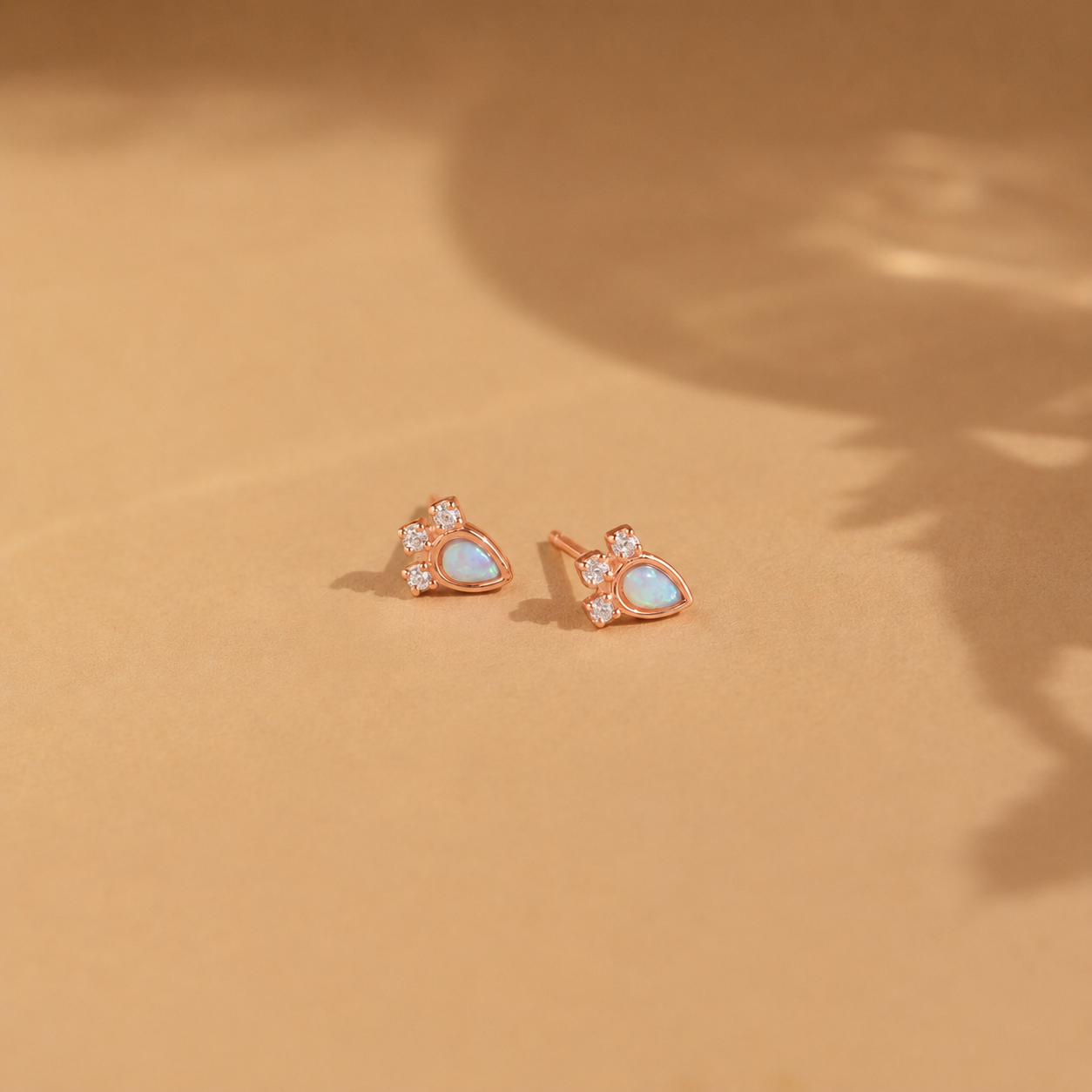 Rose gold earrings with heart-shaped gemstones on a beige background