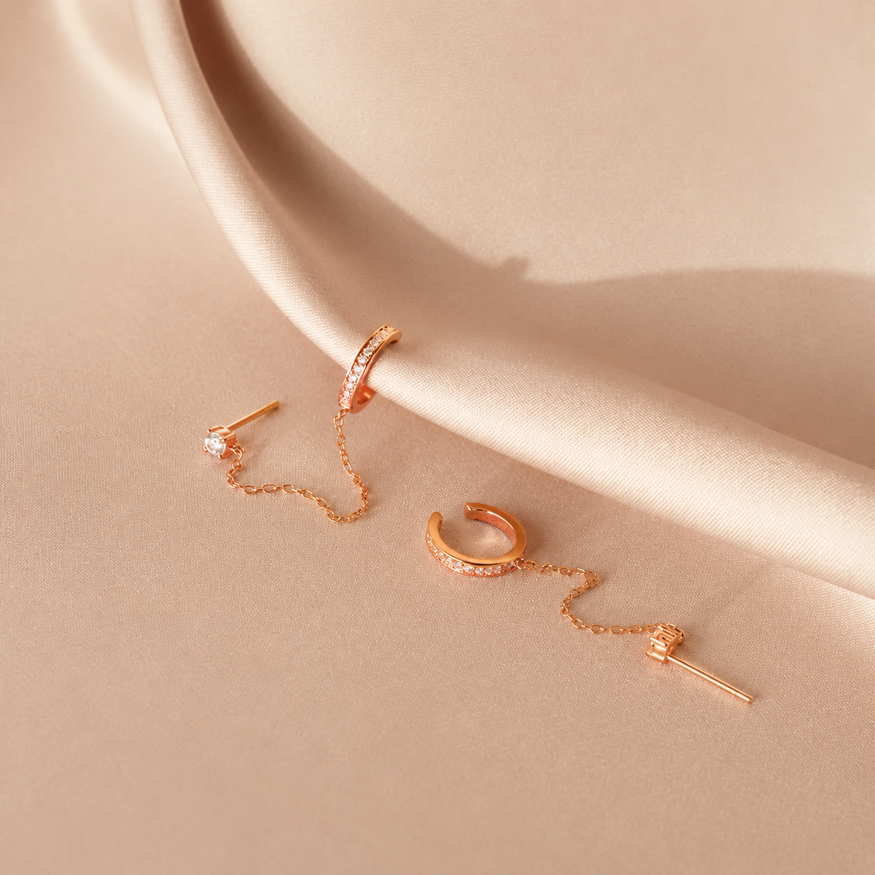 Rose gold earrings on a beige surface