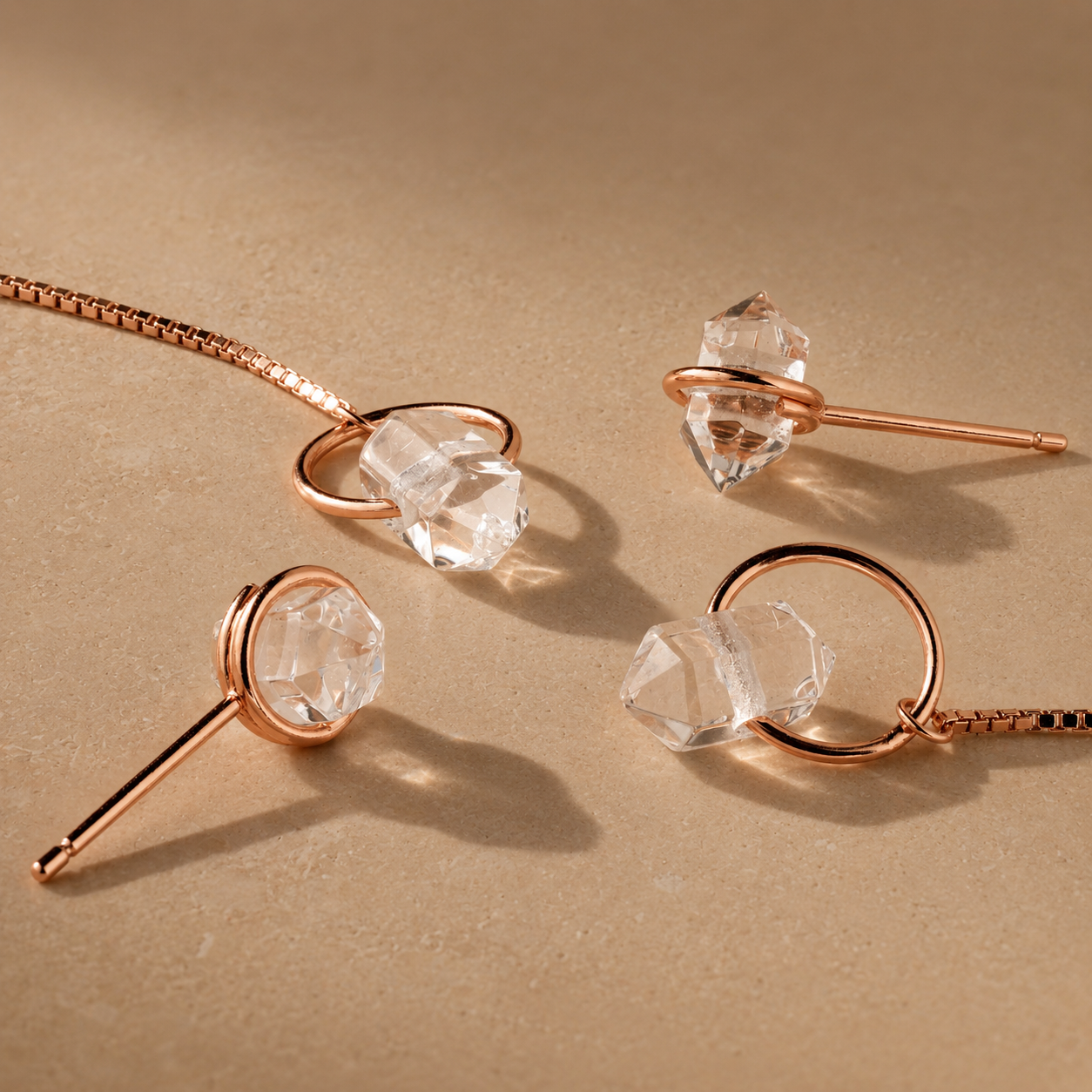 Jewelry set with rose gold necklaces and clear crystal pendants on a beige background