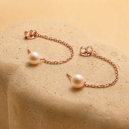 Pearl bracelet and earrings on a beige stone surface