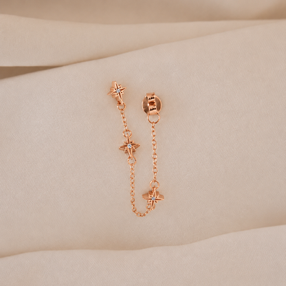 Rose gold chain earrings on a beige surface