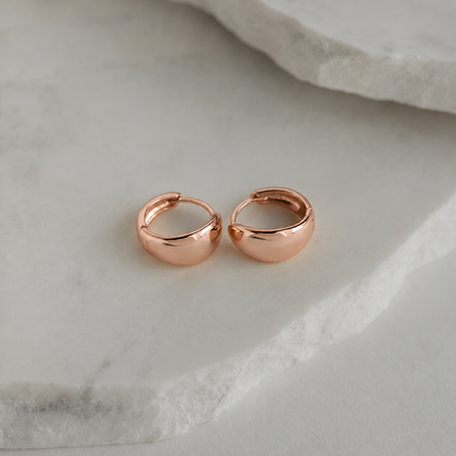 Rose gold hoop earrings on a marble surface
