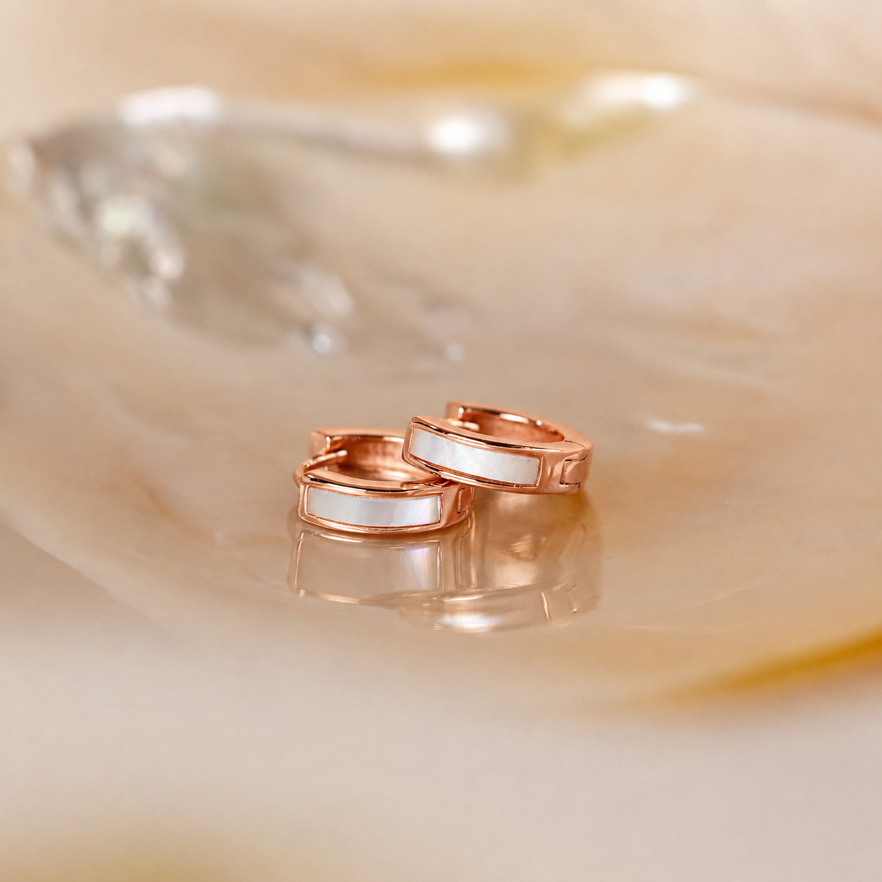 Rose gold rings with white stones on a beige shell