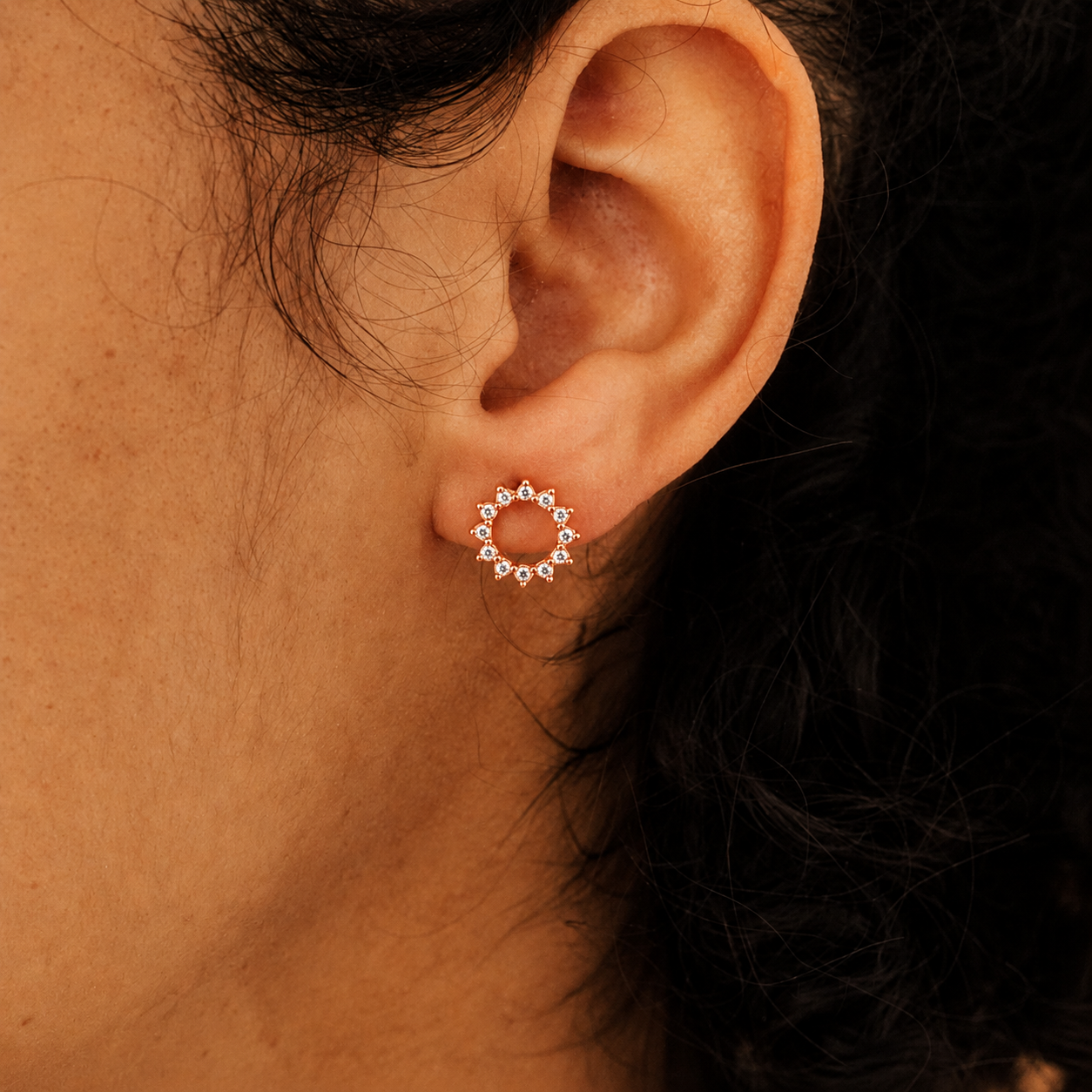 Close-up of an ear wearing a circular earring with small stones.
