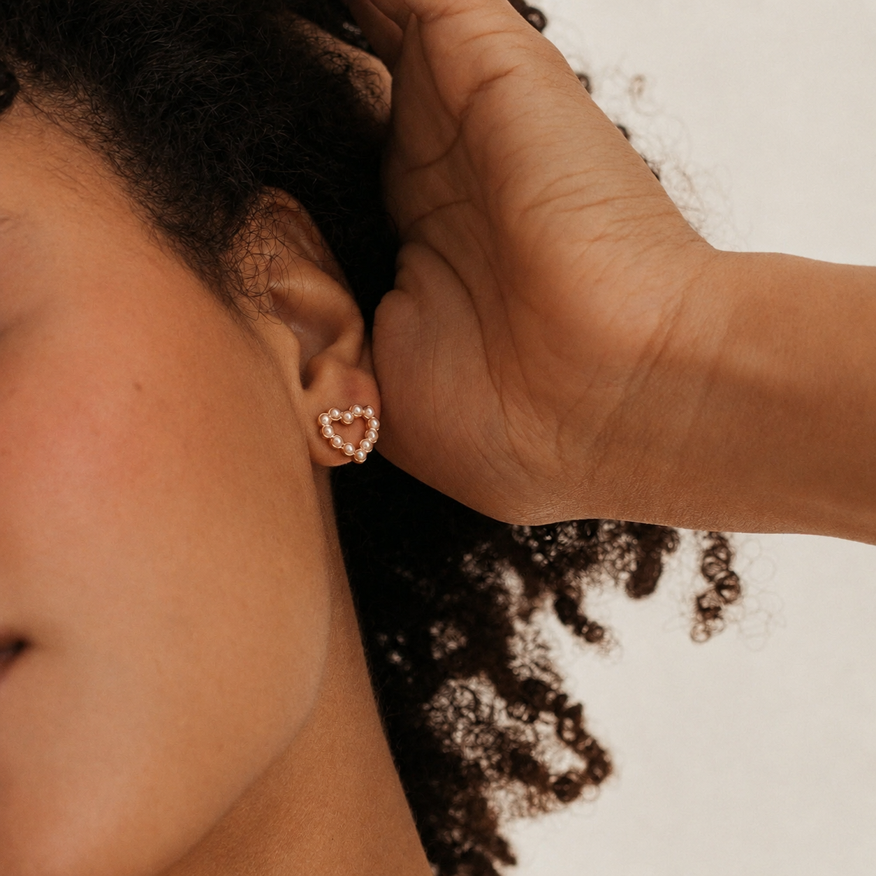 Person wearing a heart-shaped earring with a blurred background