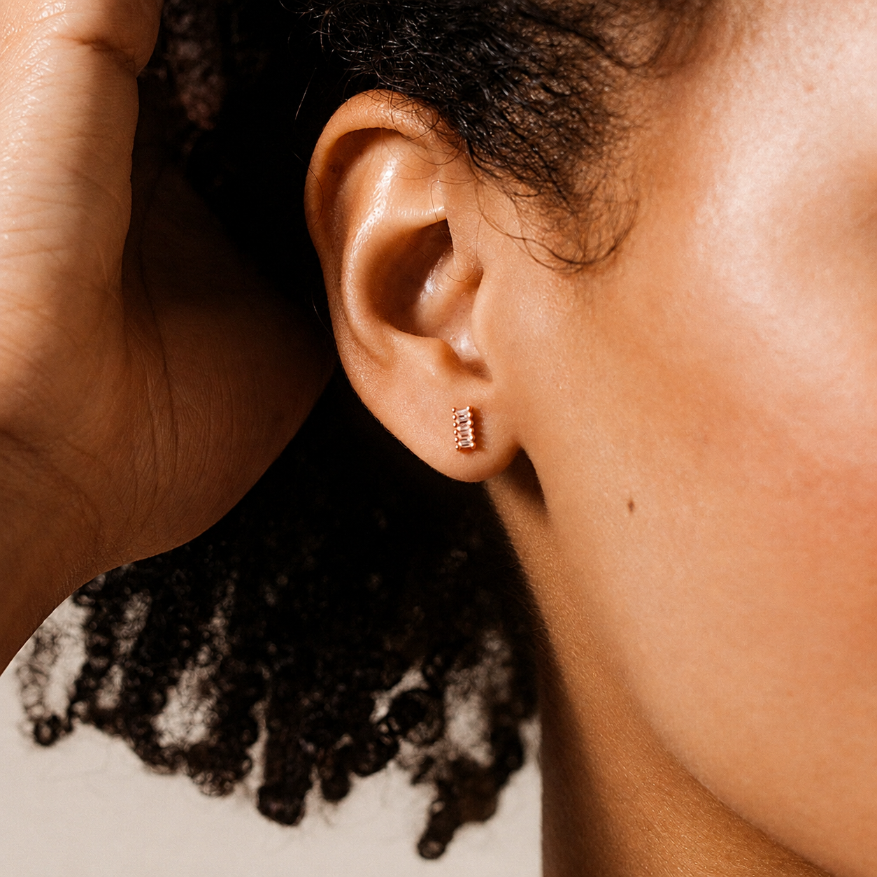 Close-up of an ear with a gold earring, focusing on the jewelry.