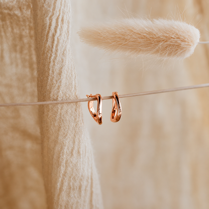 Rose gold hoop earrings on a thin wire with a soft, blurred background