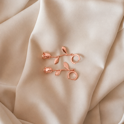 Rose gold floral earrings on beige fabric