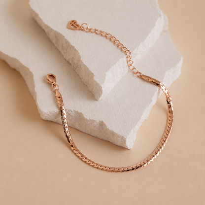 Rose gold bracelet on a textured beige surface