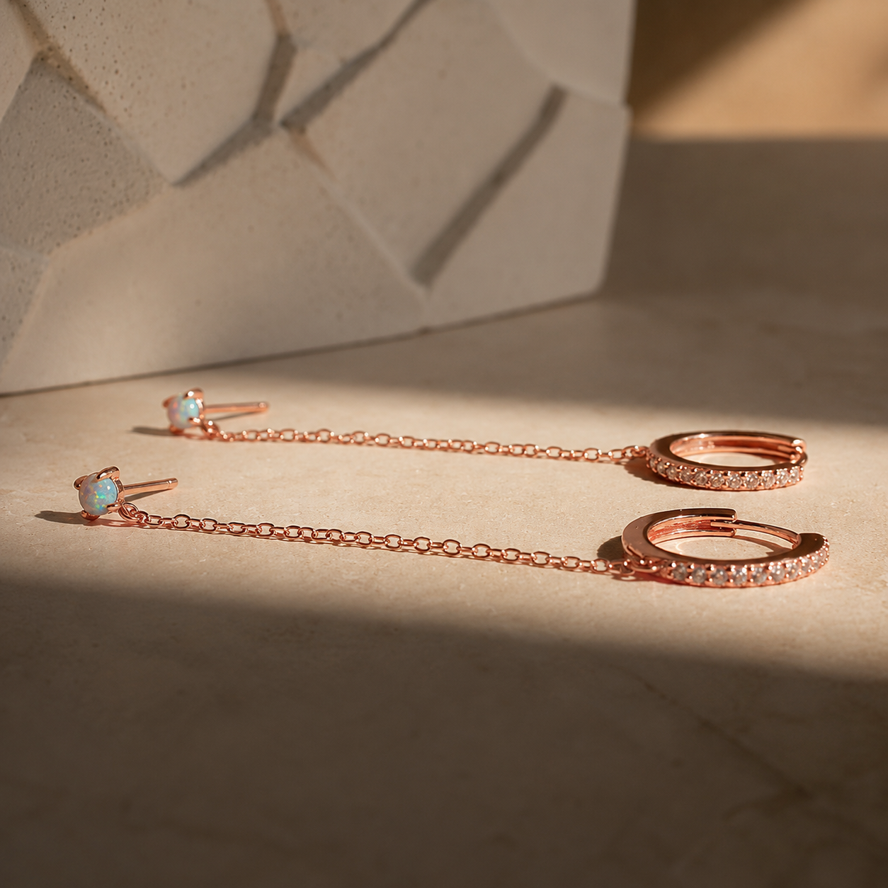 Rose gold jewelry set with earrings and a necklace on a textured surface