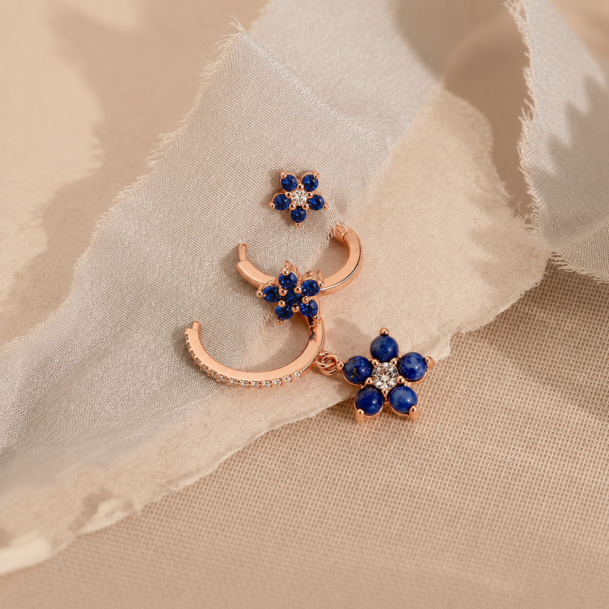 Jewelry set with rose gold crescent moon and floral designs on a beige fabric background