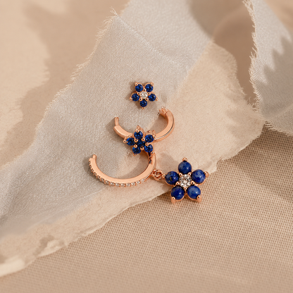 Jewelry set with rose gold crescent moon and floral designs on a beige fabric background