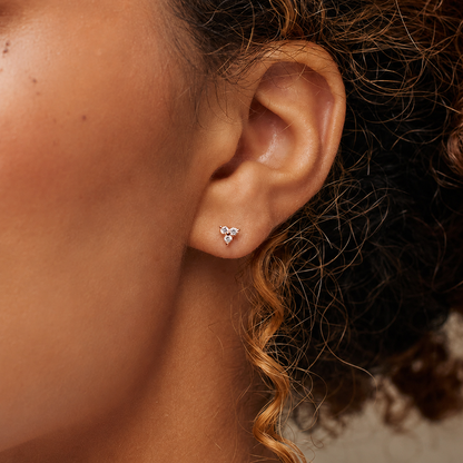 Close-up of an ear wearing a diamond earring with blurred background