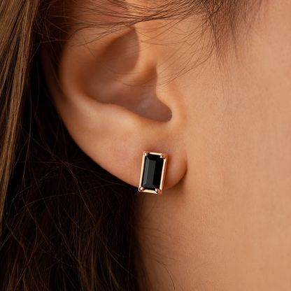 Rose gold earring with black gemstone worn by a person