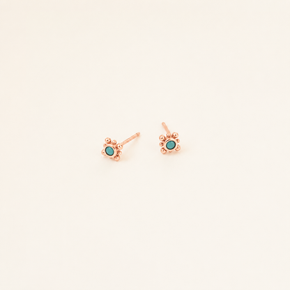 Rose gold earrings with turquoise stones on a light beige background
