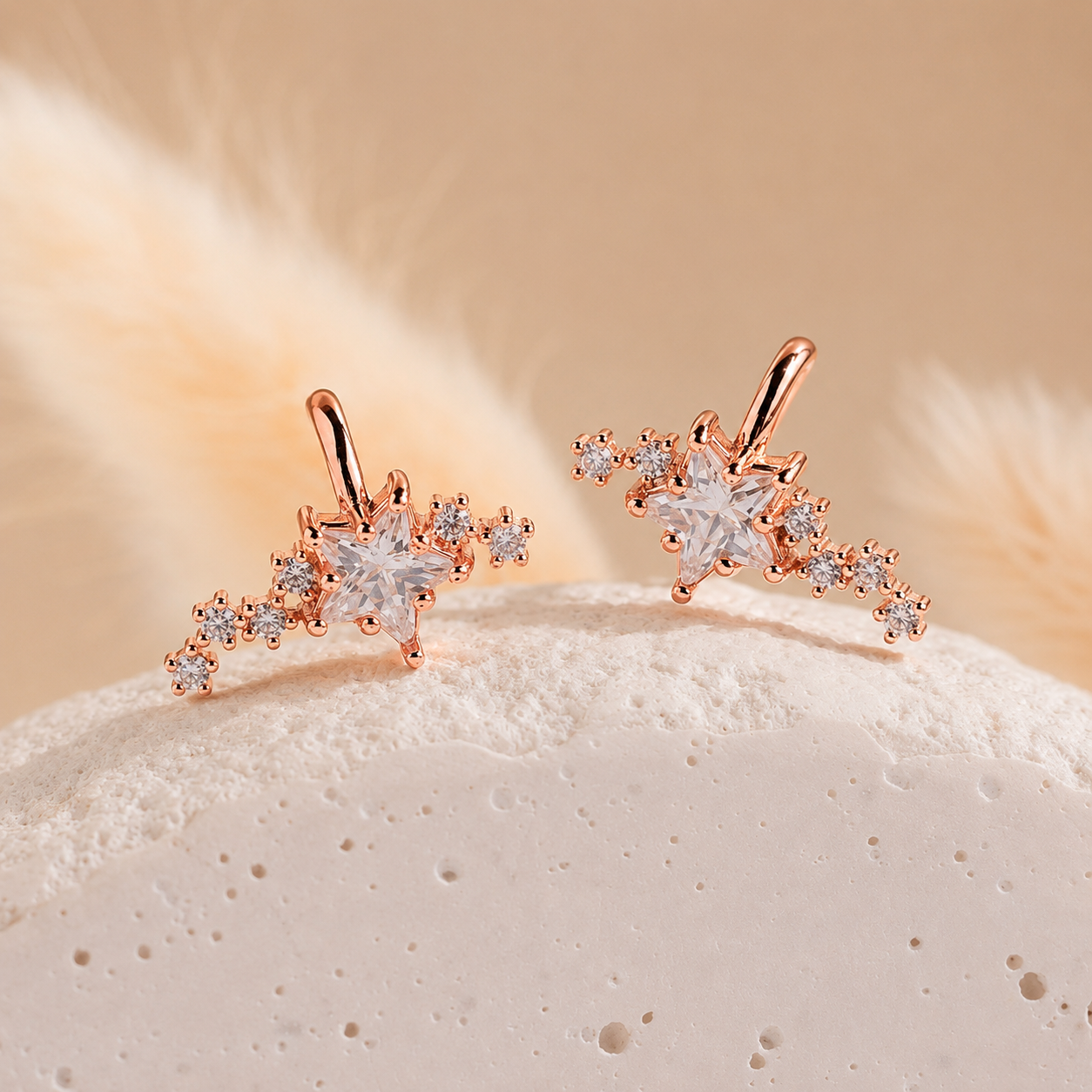 Rose gold earrings with star designs on a textured surface with a soft background