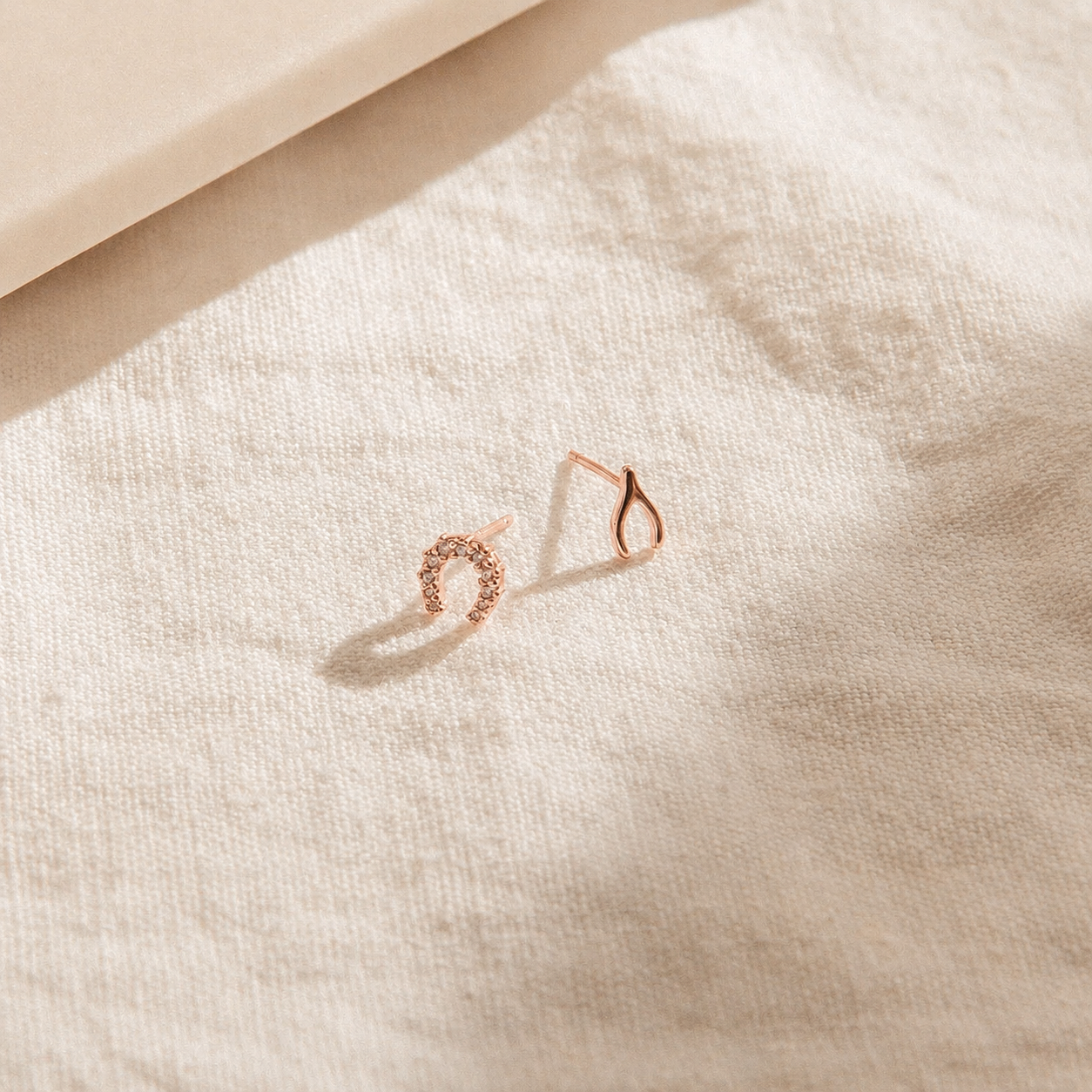 Rose gold hoop earrings on a textured beige surface