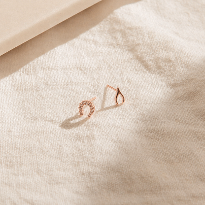 Rose gold hoop earrings on a textured beige surface