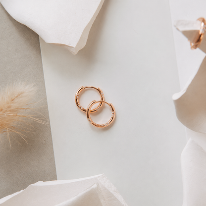 Rose gold hoop earrings on a soft white background