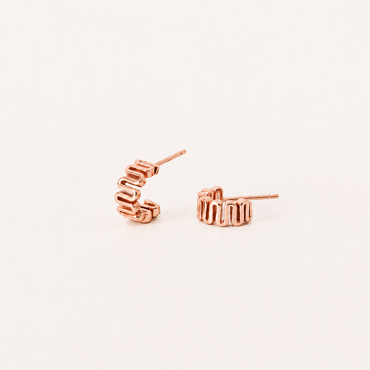 Rose gold earrings on a light beige background
