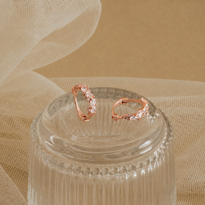 Rose gold rings with gemstones on a clear glass stand against a beige fabric background