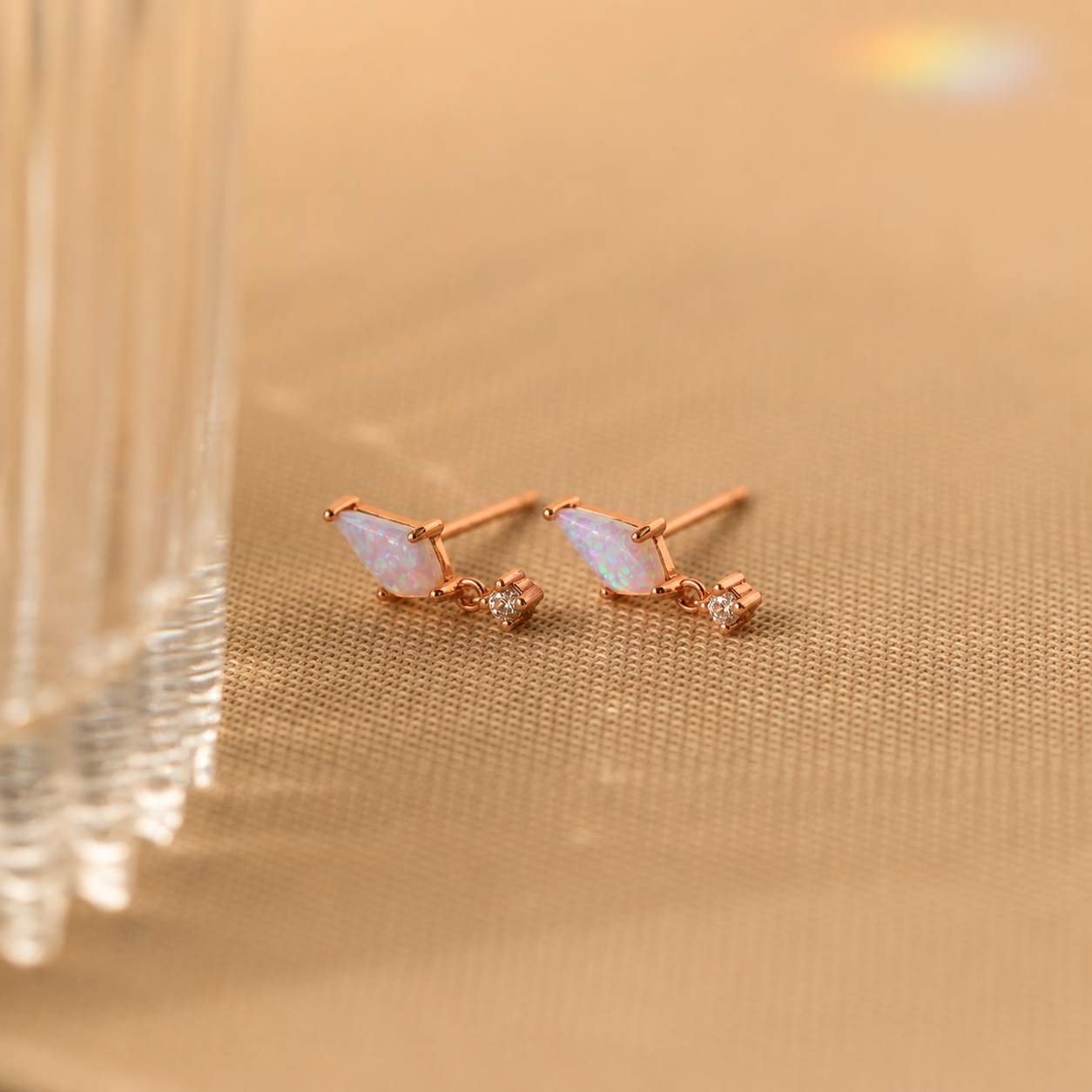 Rose gold earrings with opal stones on a gold background