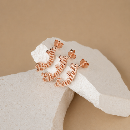 Rose gold hoop earrings on a white stone with a beige background