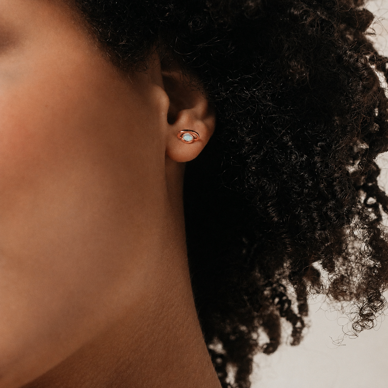 Close-up of an ear with a gold earring against a blurred background