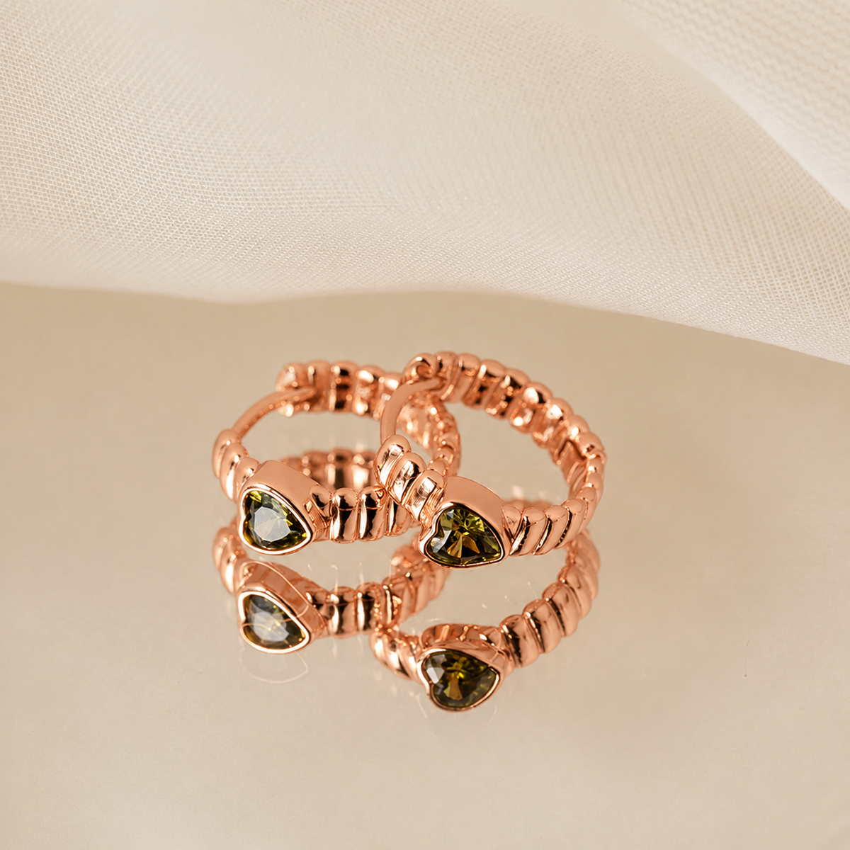 Rose gold ring with green gemstones on a beige background