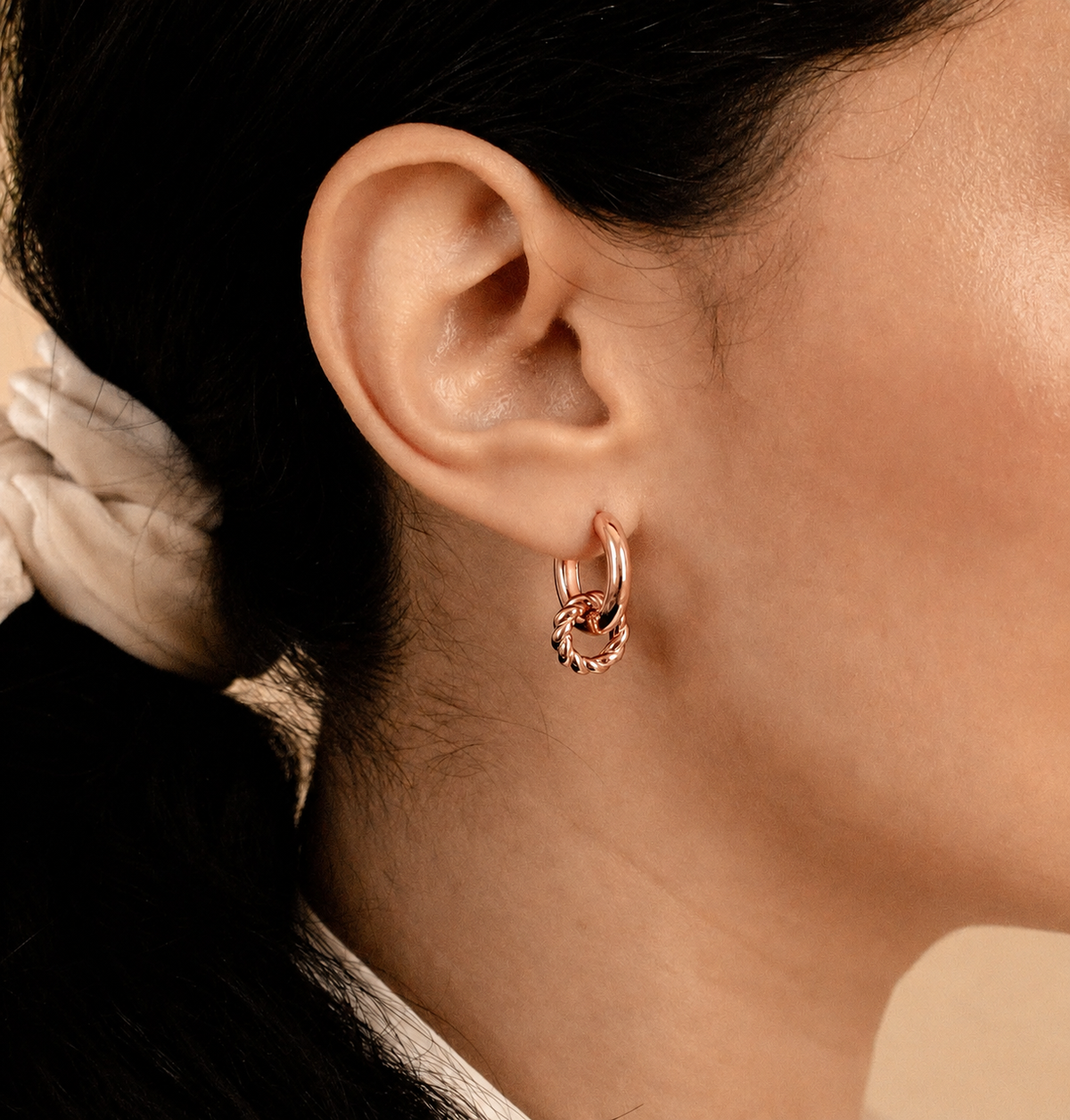 Close-up of an ear wearing a gold hoop earring with a blurred background