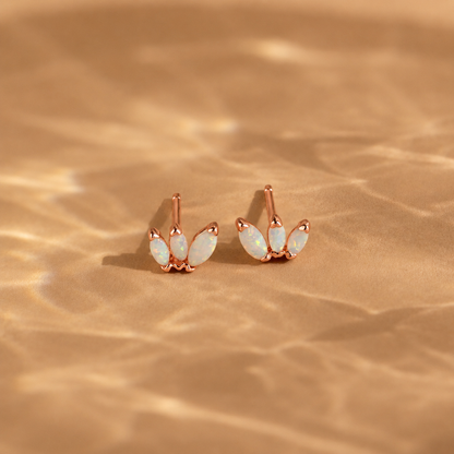 Rose gold earrings with opal stones on a beige fabric background
