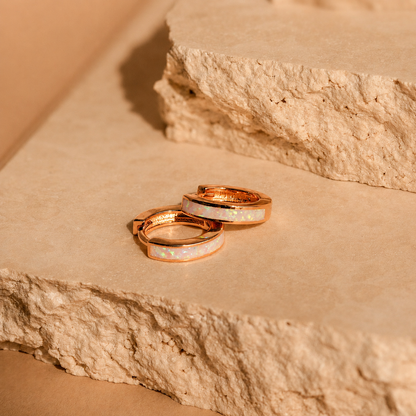 Two rose gold rings with opal stones on a stone surface
