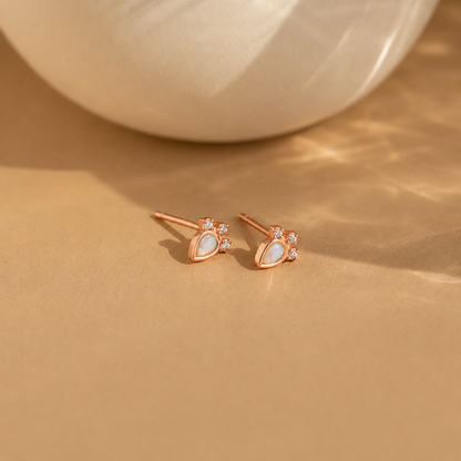 Rose gold earrings with gemstones on a beige surface