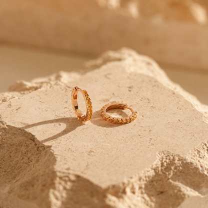Gold hoop earrings on a textured beige surface