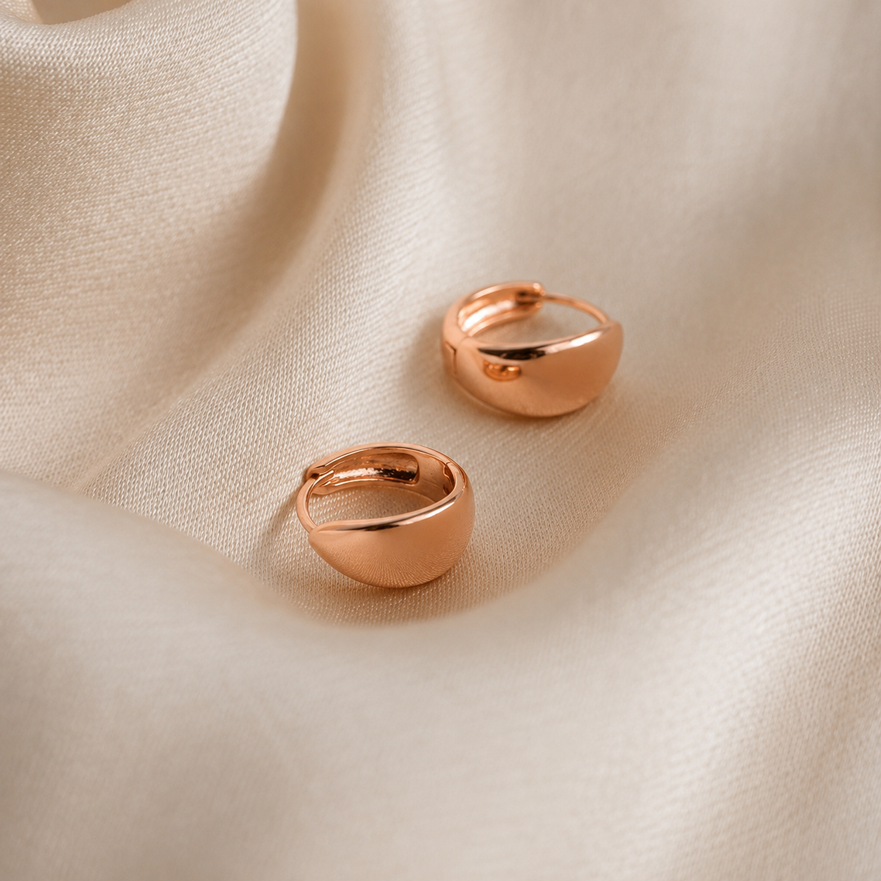 Two rose gold rings on a beige fabric background