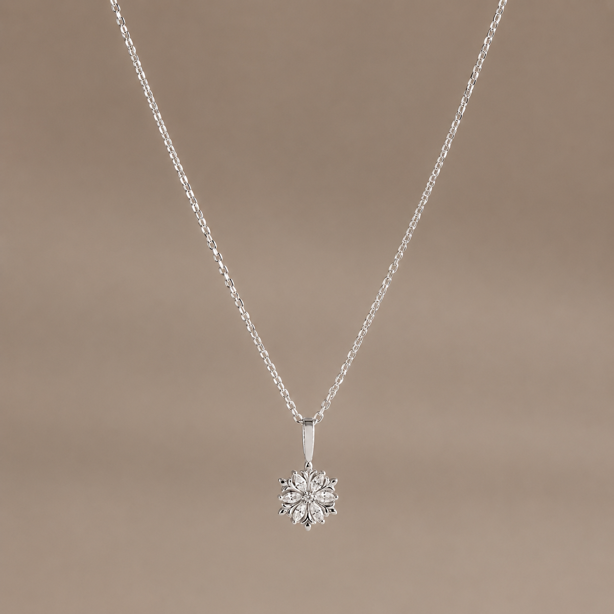 Silver necklace with a flower-shaped pendant on a beige background
